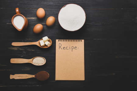Ingredients for preparing bakery and notebook on dark wooden backgroundの写真素材
