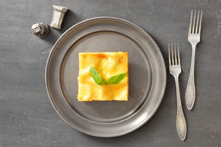 Plate with piece of tasty homemade lasagna on gray background