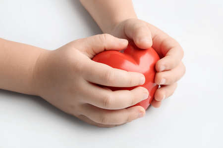 Child's hands with red heart on white background. Cardiology conceptの写真素材