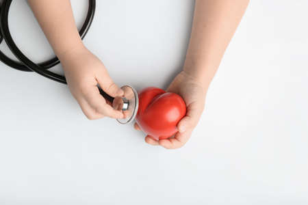Child's hands with red heart and stethoscope on white background. Cardiology conceptの写真素材