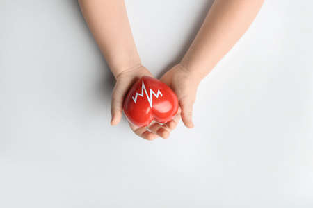 Child's hands with red heart on white background. Cardiology concept