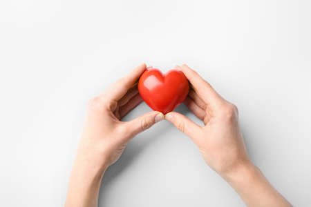 Female hands with red heart on white background. Cardiology conceptの写真素材