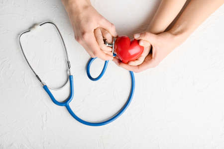 Hands of woman and child with red heart and stethoscope on white background. Cardiology conceptの写真素材