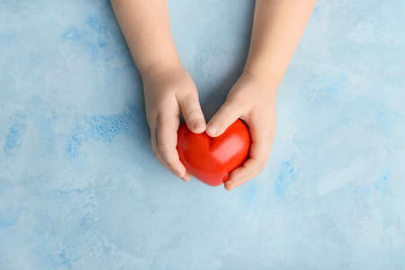 Child's hands with red heart on color background. Cardiology conceptの写真素材