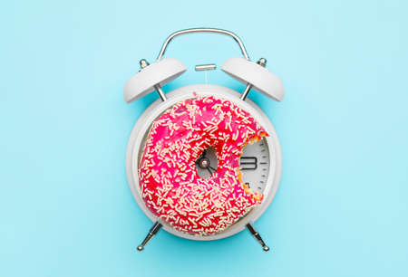 Alarm clock with donut on color backgroundの写真素材