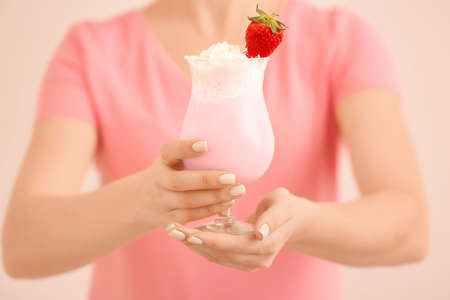 Woman with glass of tasty milkshake on color background, closeupの写真素材