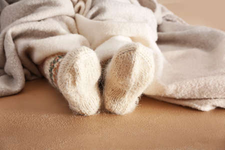 Legs of woman in knitted socks and plaid on color backgroundの写真素材