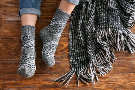 Legs of woman in knitted socks and plaid on wooden backgroundの写真素材