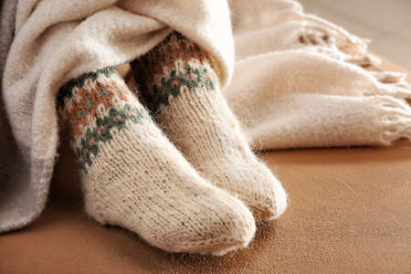 Legs of woman in knitted socks and plaid on color background