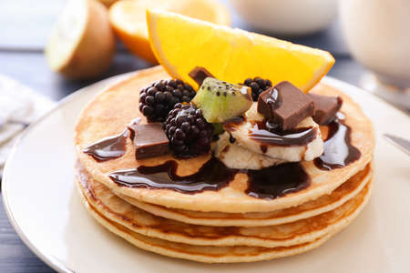Plate with stack of tasty pancakes on table