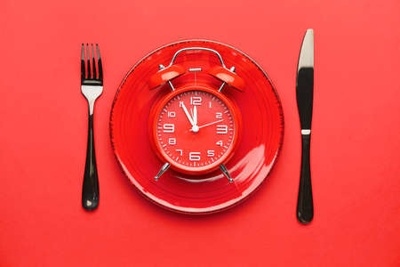 Plate and cutlery with alarm clock on color backgroundの写真素材