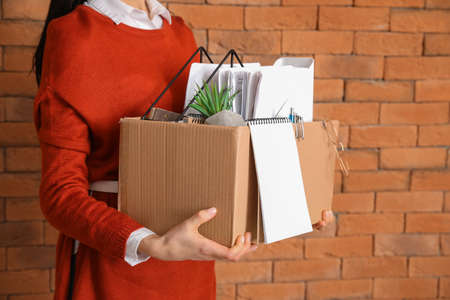 Fired woman with personal stuff on brick backgroundの写真素材