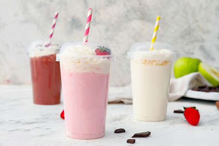 Cups of tasty milkshakes on white backgroundの写真素材