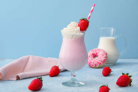 Glass of tasty strawberry milkshake on color backgroundの写真素材