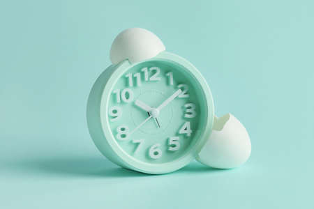 Alarm clock with broken egg shell on color backgroundの写真素材