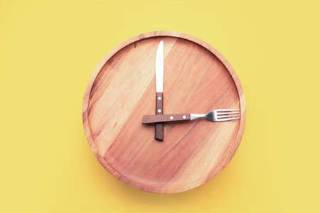 Plate with cutlery on color background. Concept of time