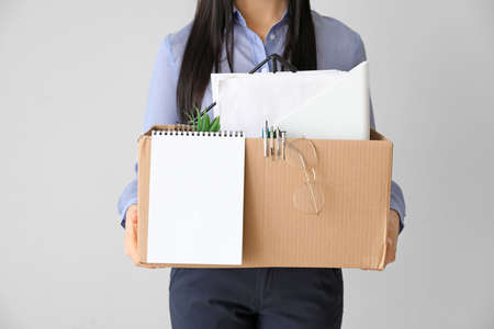 Fired woman with personal things on light backgroundの写真素材