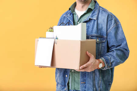 Fired man with personal things on color background