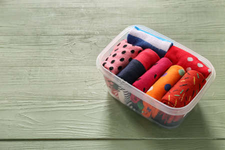Box with different socks on wooden background