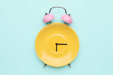 Creative alarm clock made with plate on color backgroundの写真素材