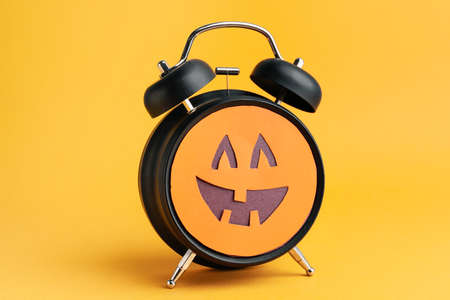 Alarm clock with scary face on color background. Halloween celebrationの写真素材