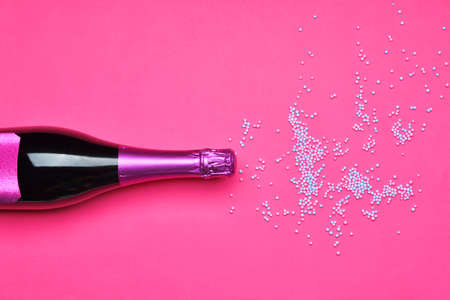 Bottle of tasty champagne with sprinkles on color backgroundの写真素材