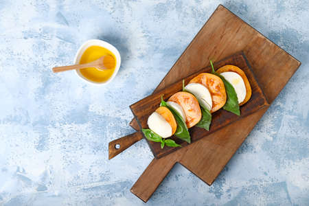 Mozzarella cheese with tomatoes, basil and oil on color backgroundの写真素材