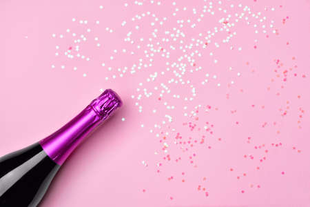 Bottle of tasty champagne with glitters on color backgroundの写真素材