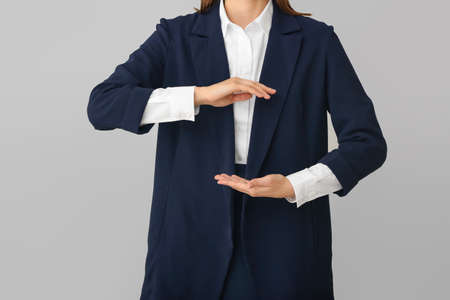 Businesswoman holding something on gray background, closeupの写真素材