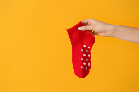 Female hand with sock on color backgroundの写真素材