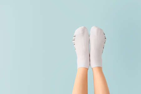 Legs of young woman in socks on color background