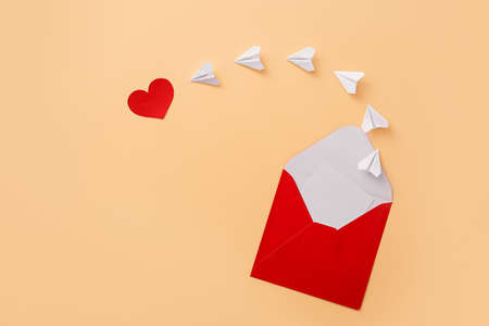 Composition with envelope, paper airplanes and heart on color background