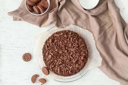 Tasty chocolate cheesecake with cookies on white table