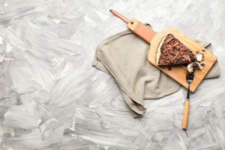 Piece of tasty chocolate cheesecake on gray background