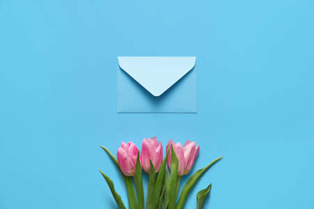 Envelope with flowers on color background