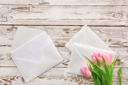 Envelopes with card and flowers on white wooden backgroundの写真素材