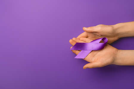 Female hands with violet ribbon on color background. Domestic violence conceptの写真素材