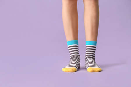 Legs of young woman in striped socks on color backgroundの写真素材