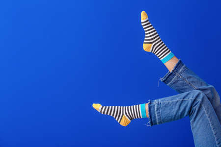 Legs of young woman in striped socks on color backgroundの写真素材