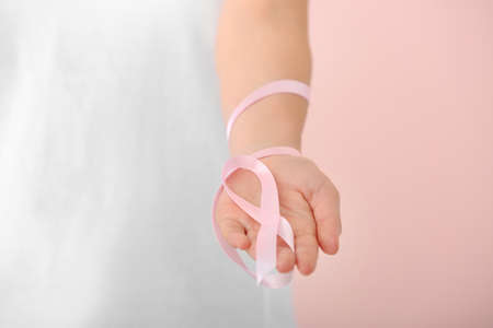 Young woman with pink ribbon on color background, closeup. Cancer awareness conceptの写真素材