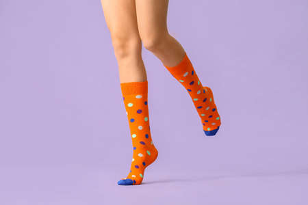 Legs of young woman in socks on color background