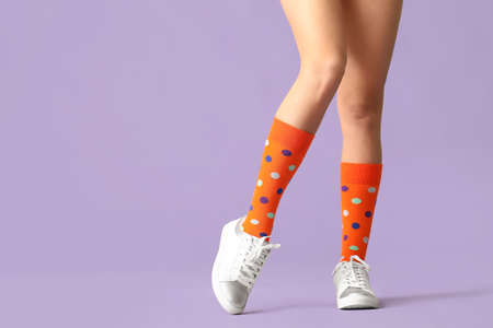 Legs of young woman in socks and shoes on color backgroundの写真素材