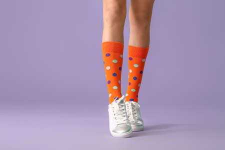 Legs of young woman in socks and shoes on color backgroundの写真素材