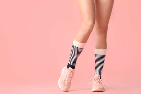 Legs of young woman in socks and shoes on color backgroundの写真素材
