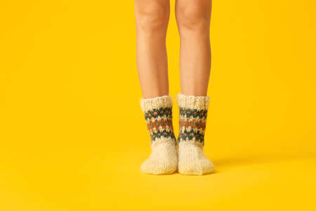 Legs of young woman in warm knitted socks on color backgroundの写真素材