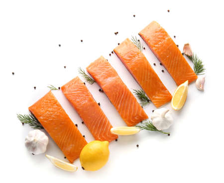 Raw salmon fillet with spices, garlic and lemon on white backgroundの写真素材