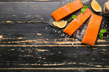 Raw salmon fillet with herbs and lemon on tableの写真素材