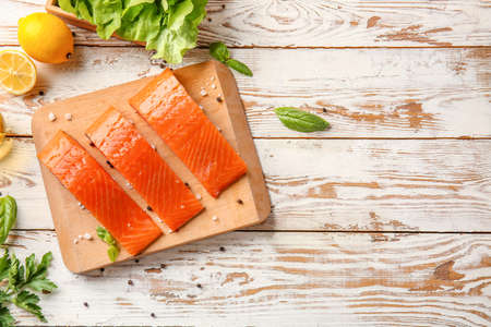Raw salmon fillet with herbs, lemon and spices on tableの写真素材