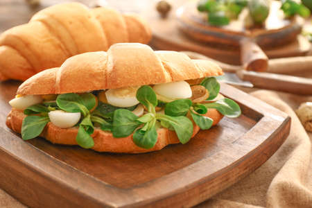 Tasty croissant sandwich on wooden board