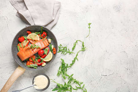 Frying pan with cooked salmon fillet and vegetables on white backgroundの写真素材